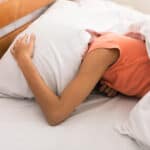 Lack of sleep. Woman covering head with pillow